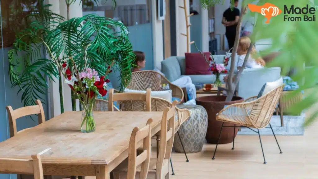 Bright Bali café with wooden tables, plants, and guests relaxing in a cozy seating area.