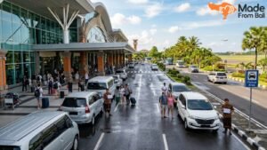 Travelers meeting airport drivers and transfer cars outside Bali airport arrival pickup area.