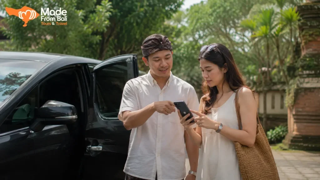 Wisatawan memeriksa informasi di ponsel bersama driver Bali sebelum memulai perjalanan dengan mobil pribadi.