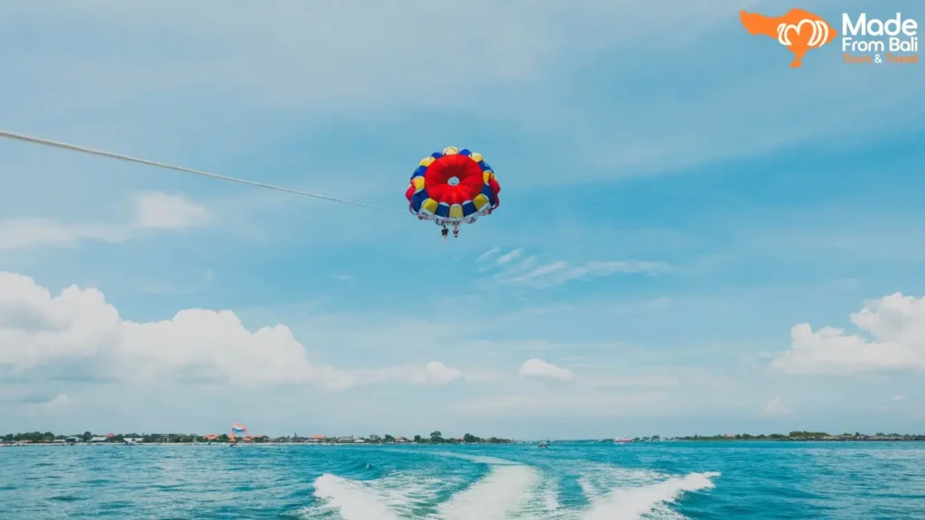 Visitors enjoy parasailing over the sea in Tanjung Benoa, one of Bali's most popular water sports activities.