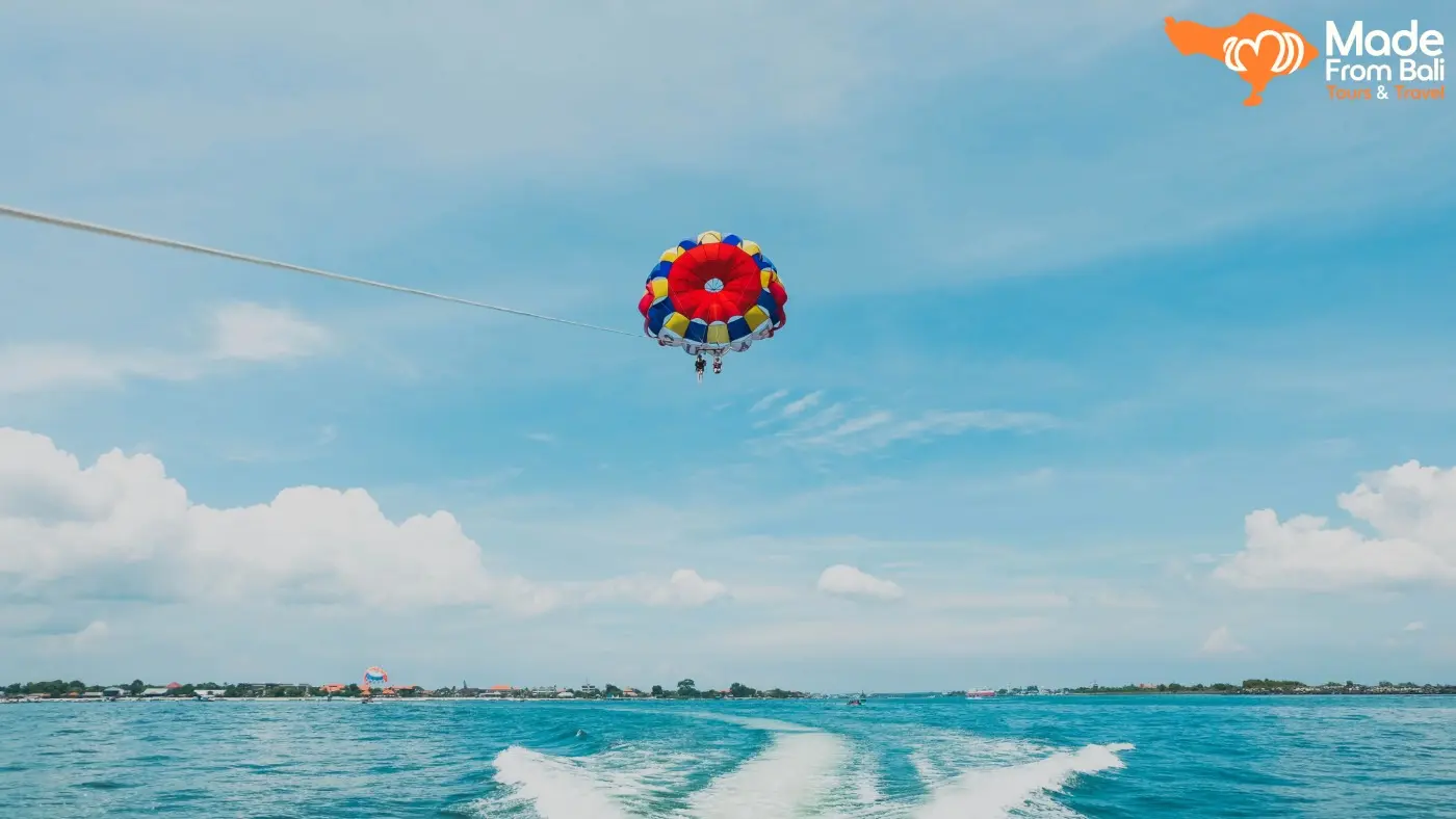 Visitors enjoy parasailing over the sea in Tanjung Benoa, one of Bali's most popular water sports activities.