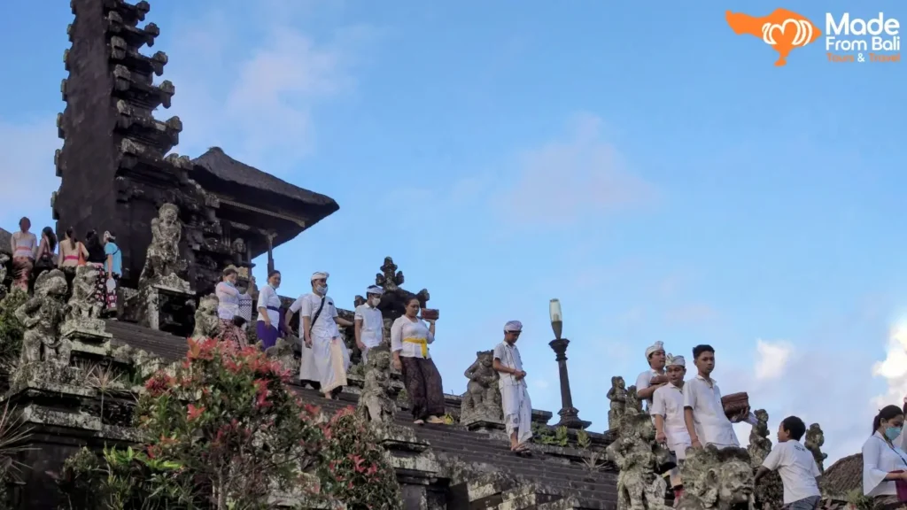 Wisatawan berjalan tertib di area pura Bali dengan pakaian adat sesuai etika saat berkunjung ke pura.