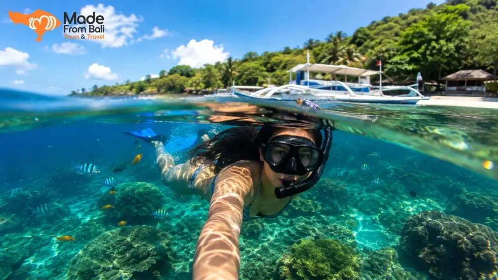 A tourist snorkels through clear turquoise water at Blue Lagoon Padang Bai, surrounded by colorful fish and coral reefs.